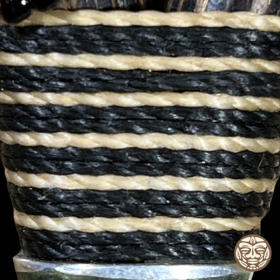 Close-up of a woven chambira rope textile with alternating thick black and natural beige horizontal stripes.